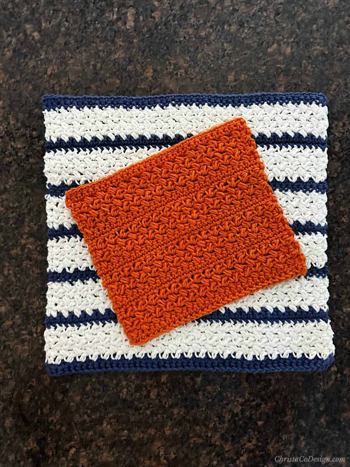 Orange towel over white and blue striped dishcloth.