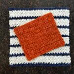 Orange towel over white and blue striped dishcloth.