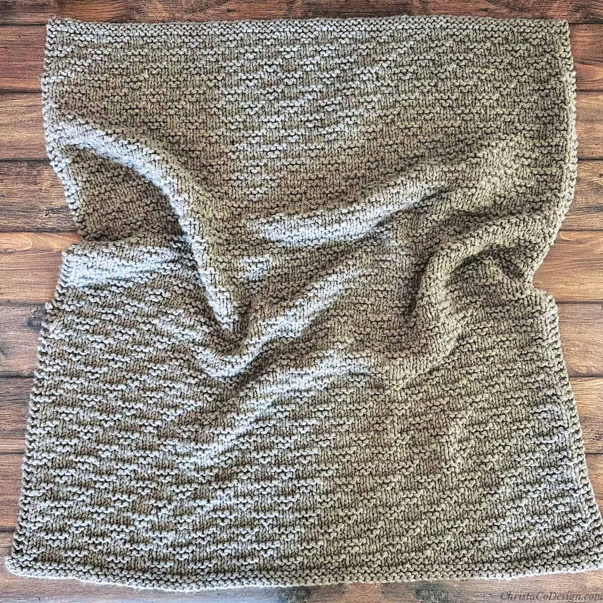 Knit blanket laid out on table.