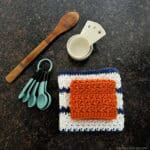 Kitchen utensils next to folded dishcloths with white and blue stripes.
