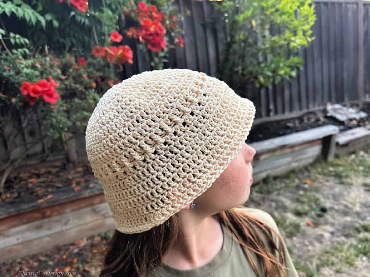 Girl turned to side in cream colored cotton bucket hat.