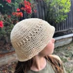 Girl turned to side in cream colored cotton bucket hat.