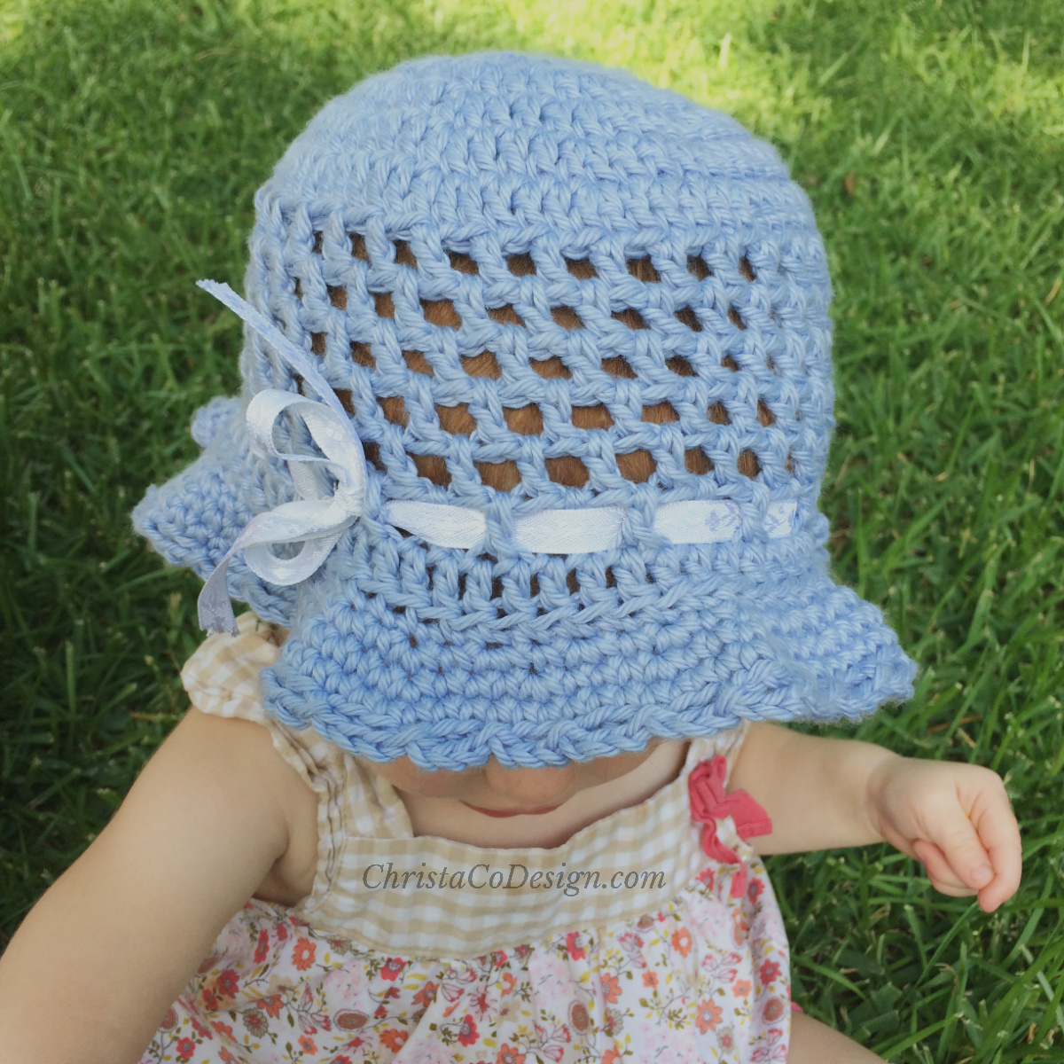 Toddler in blue sun hat with ribbon.