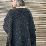Woman in crochet poncho turned to show back.