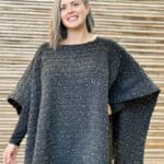 Woman smiling in black crochet poncho.