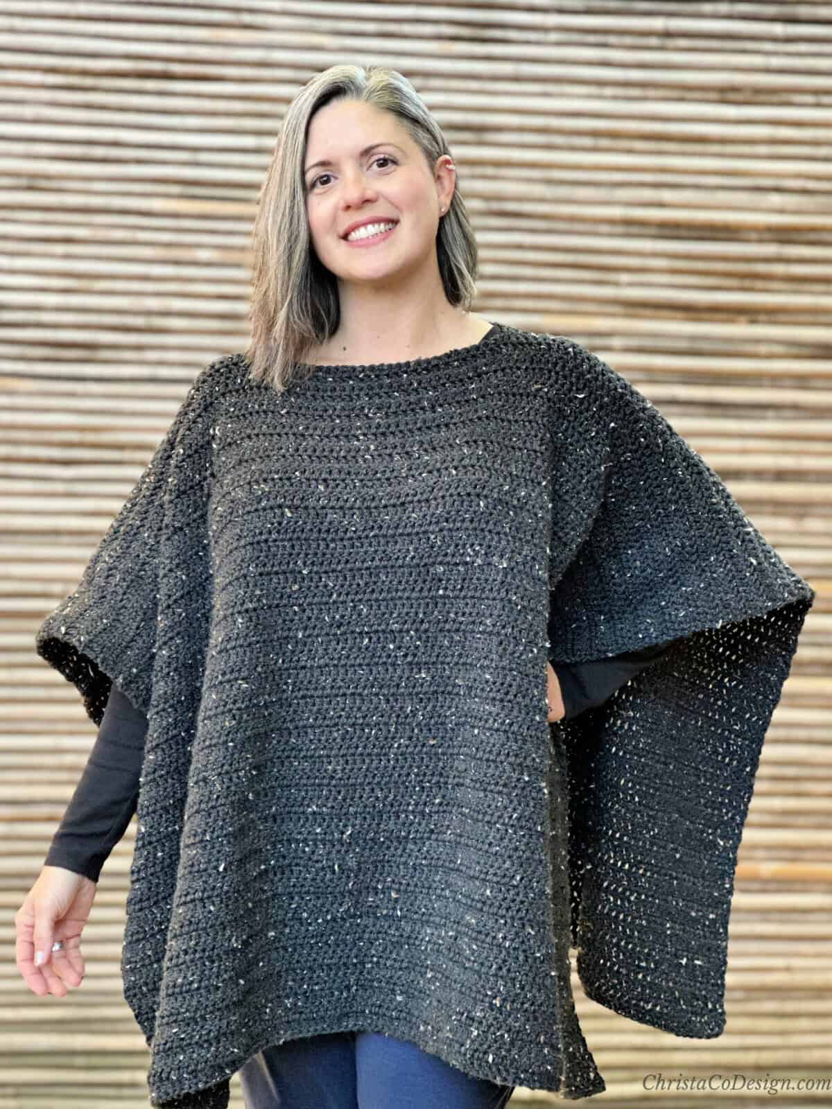 Woman smiling in black crochet poncho.
