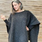 Woman looking down wearing black crochet poncho.