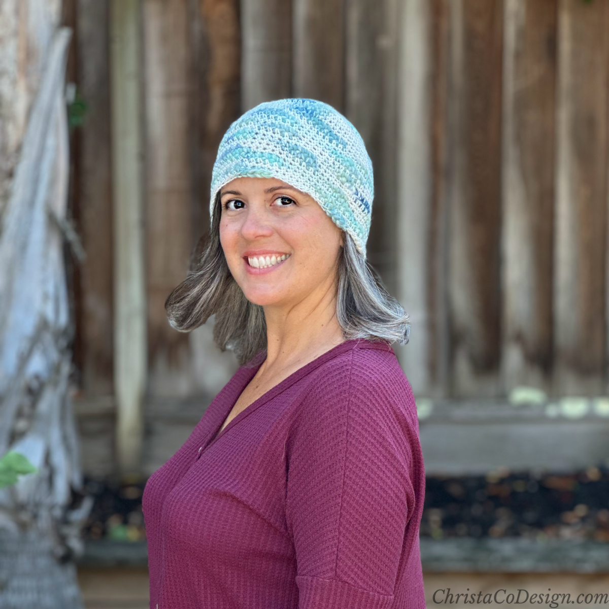 Woman turned to side in blue green white beanie.