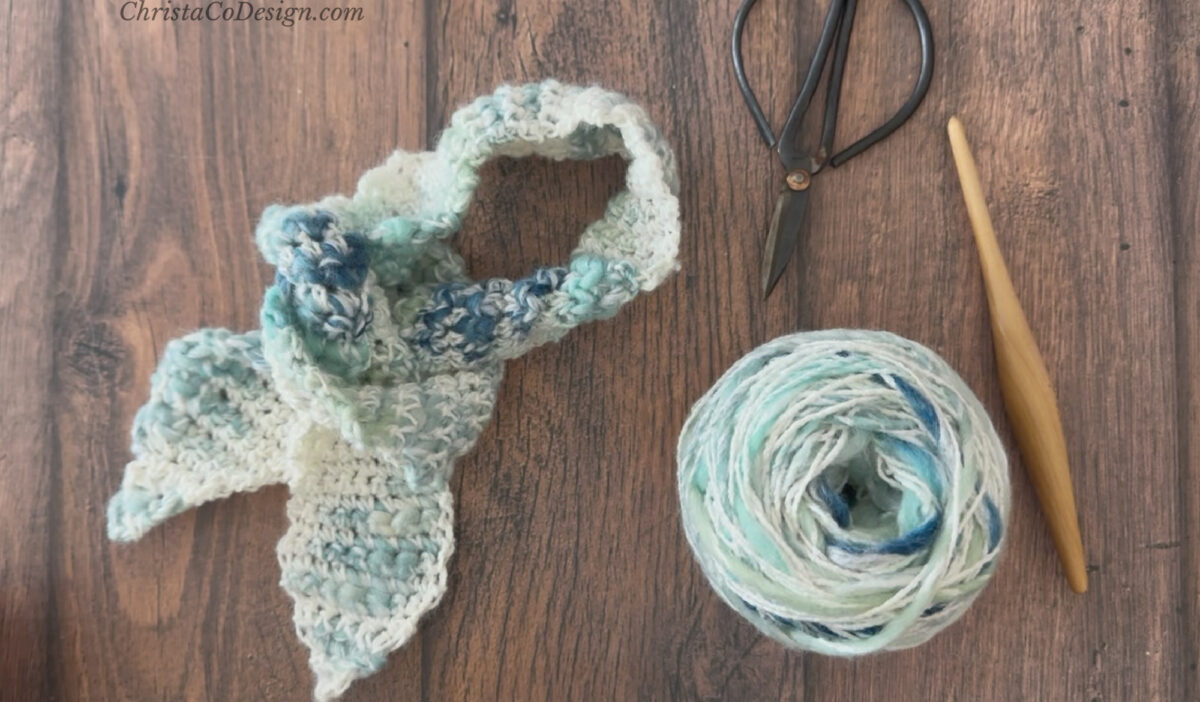 Neck scarf with scissors, yarn and hook.