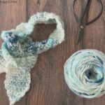 Neck scarf with scissors, yarn and hook.