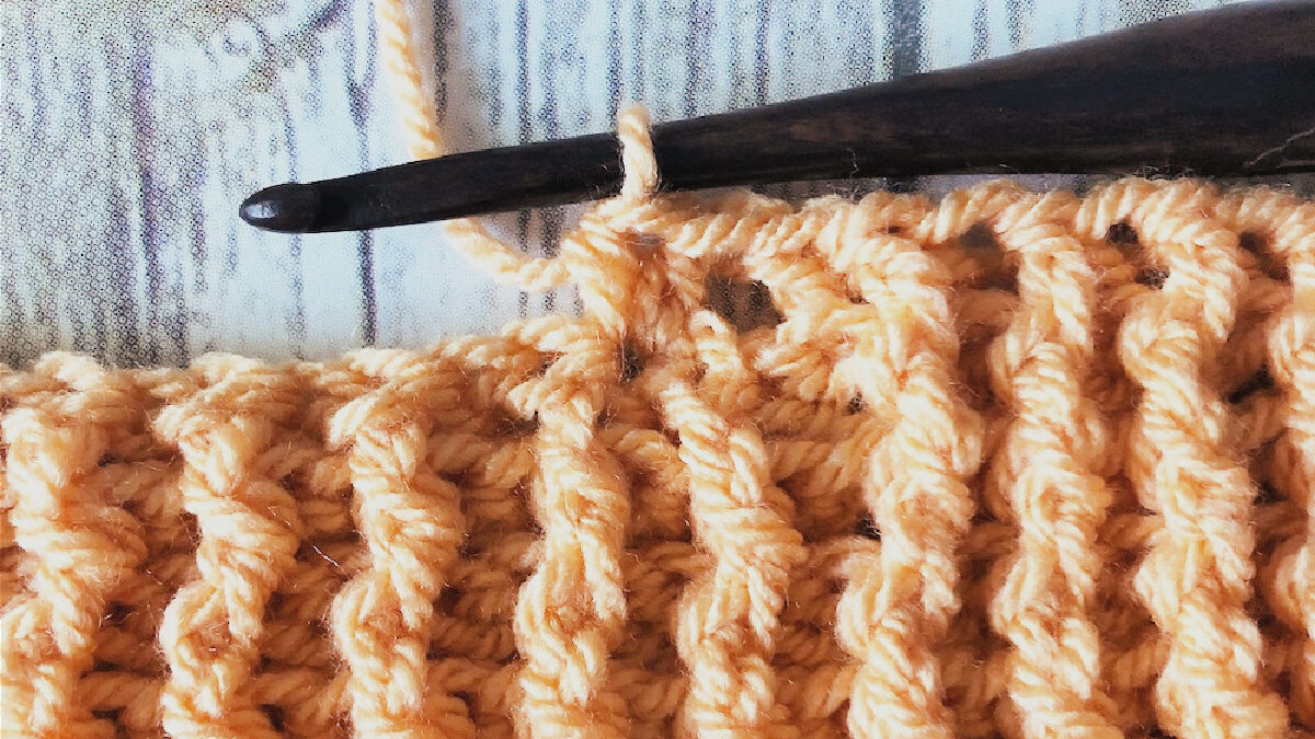 Orange crochet blanket on hook with ribbing.