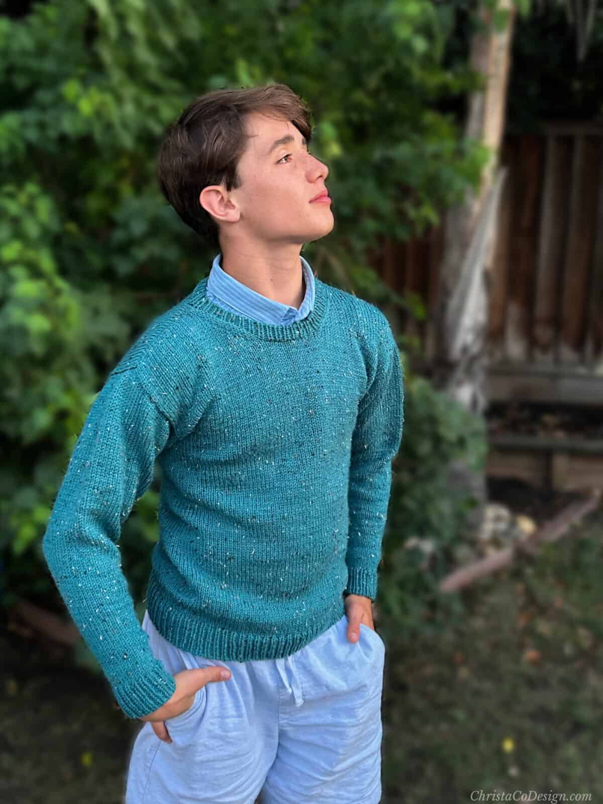 Young man in blue knit sweater looking up.