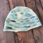Angled view of crochet beanie in blue and white bulky yarn.