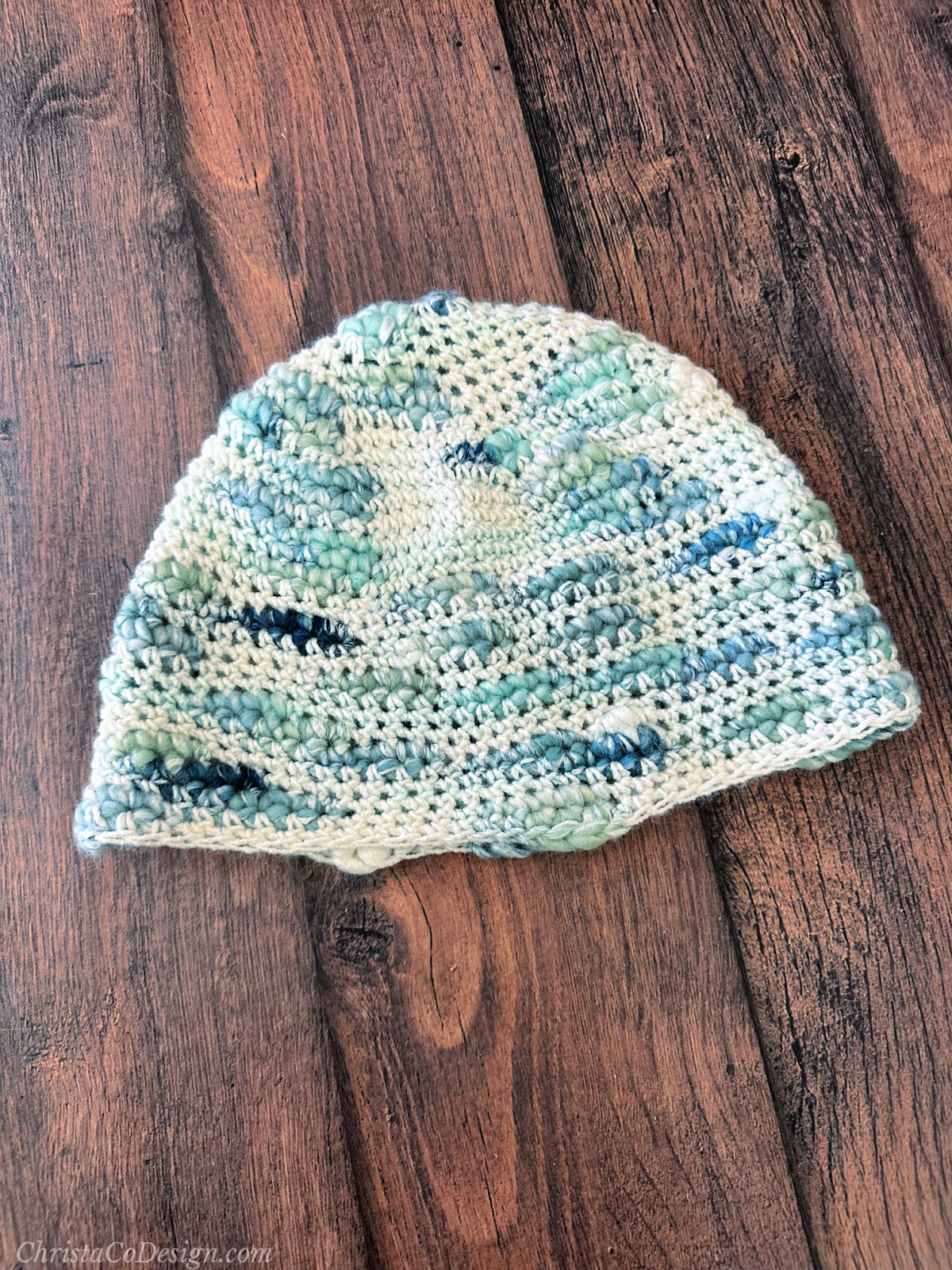 Angled view of crochet beanie in blue and white bulky yarn.