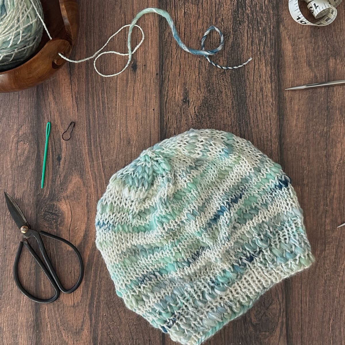 Square top down image of knit hat and notions.