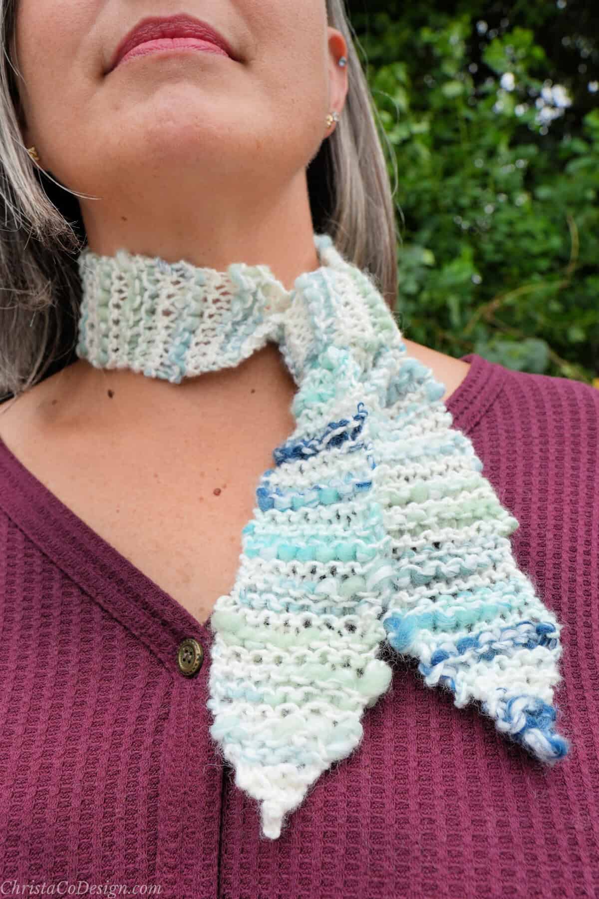 Close up of garter stitch skinny scarf knotted at neck.
