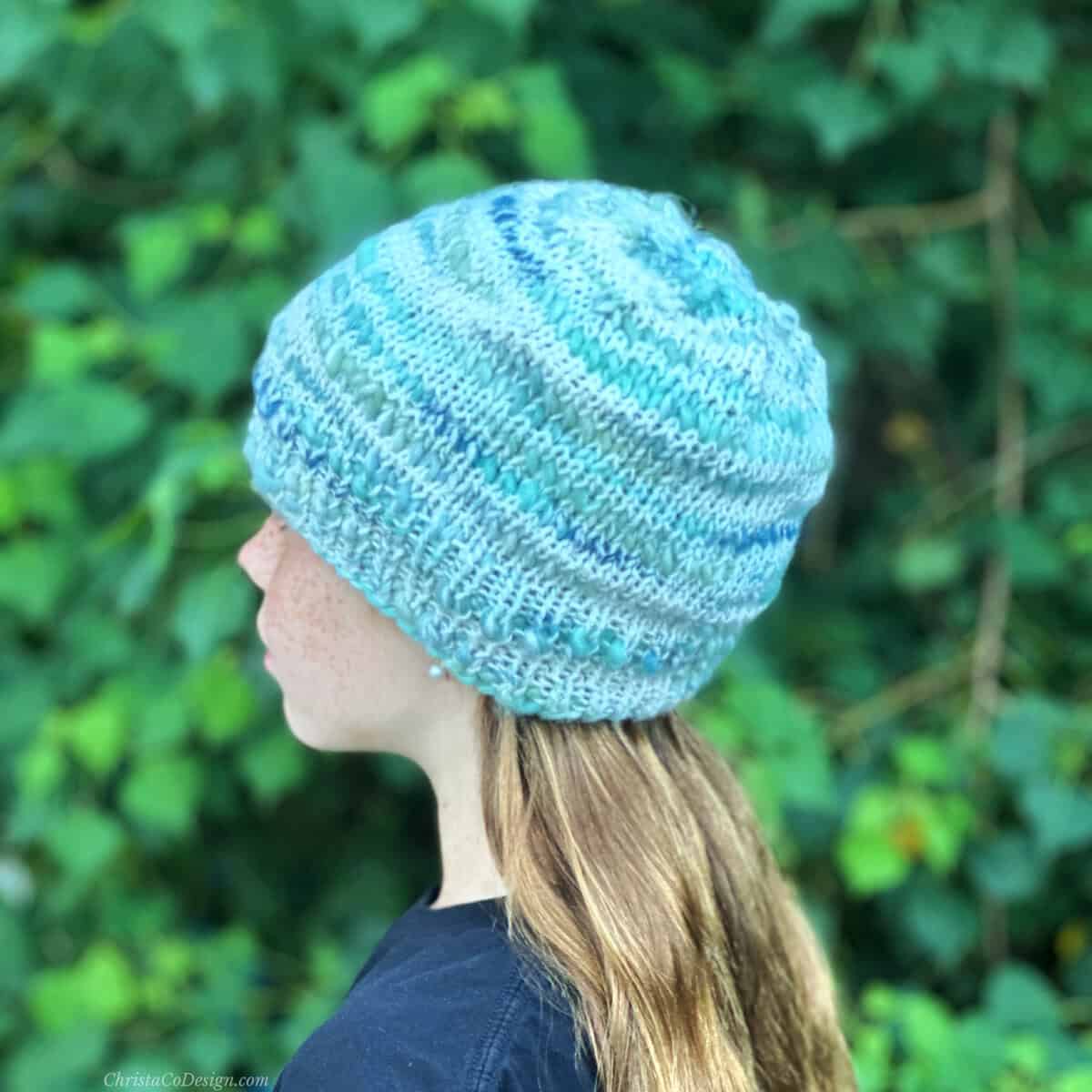 Side view of girl in blue green white knit hat.