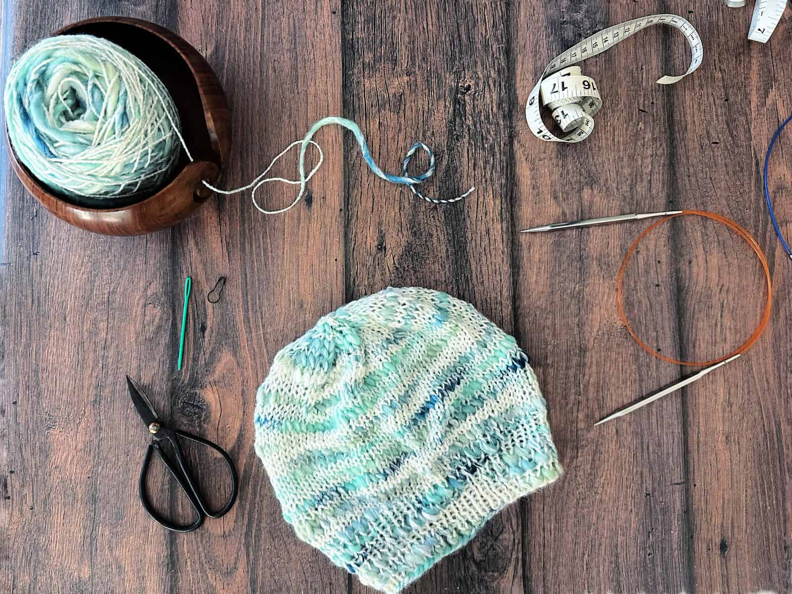 Top down view of yarn and notions with knit hat.