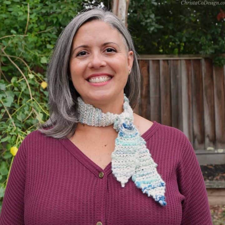 Woman smiling in red with knit scarf knotted at neck.