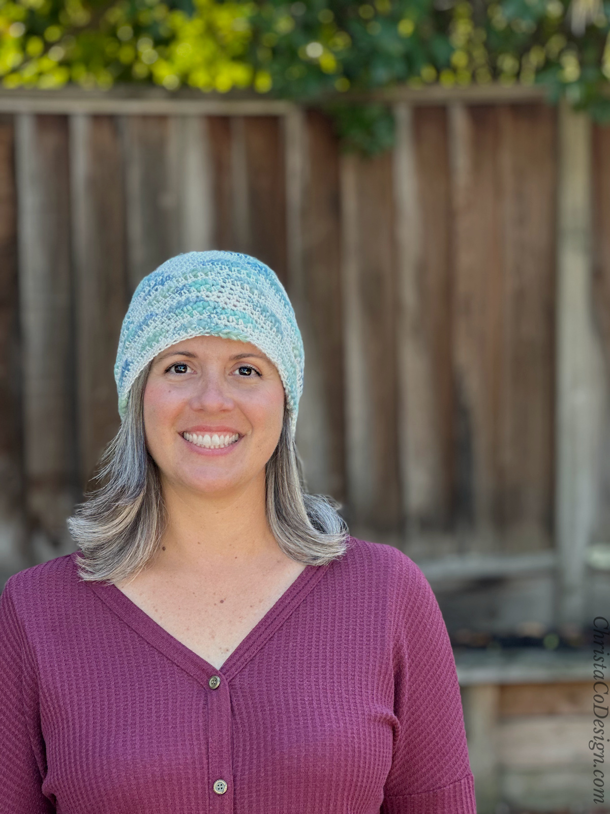 Woman in blue and white beanie smiling.