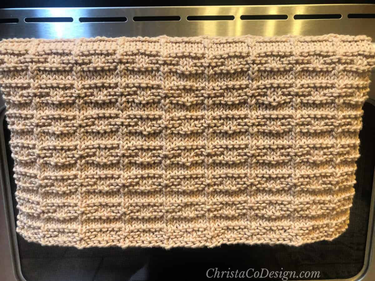 Textured dish towel draped over oven handle.