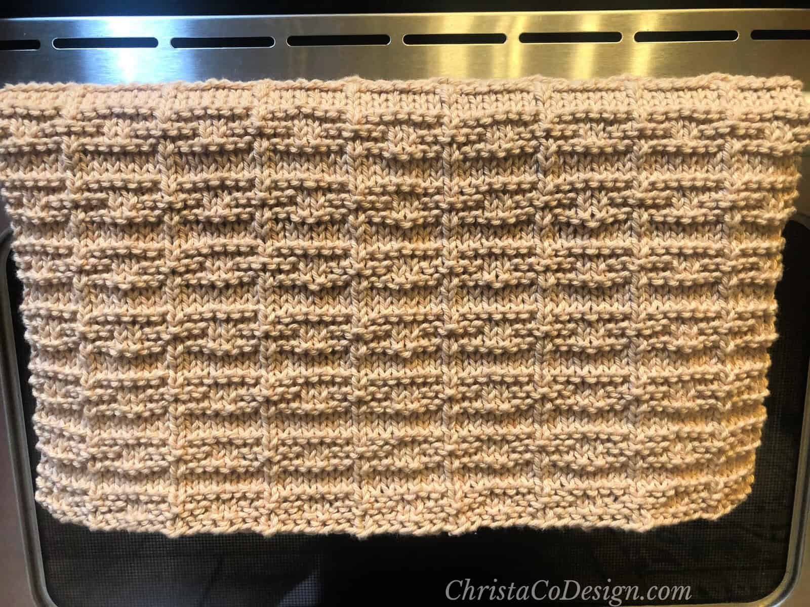 Textured dish towel draped over oven handle.